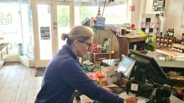 Taralga General Store sales assistant, Gabi Keith, signs a petition opposing Upper Lachlan Shire Council's withdrawal from the town's Post Office contract. Picture supplied.